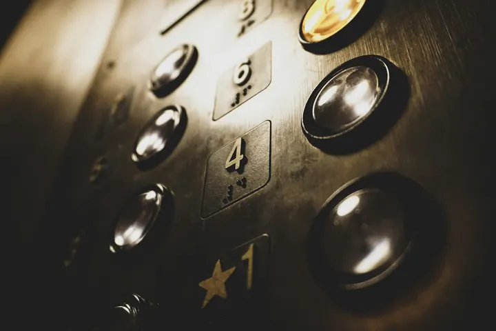 Botões de uma botoeira de elevador em metal, com números em braile